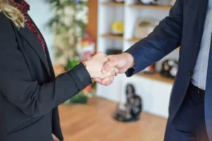 Poignée de main professionnelle entre un homme et une femme en tenue de bureau.