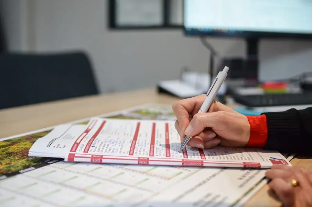 Gros plan sur une main remplissant méticuleusement un formulaire papier au stylo.