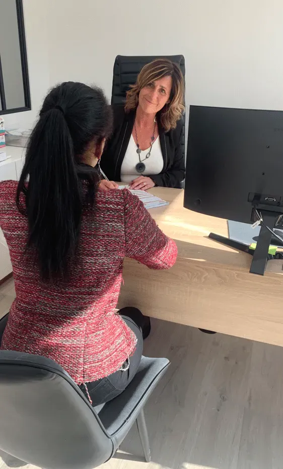 Deux femmes en entretien professionnel autour d'un bureau en bois clair.